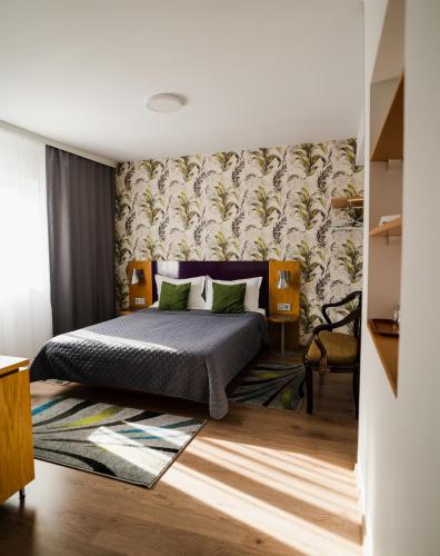 a bedroom with a bed and a wall with a wallpaper at Vila RANYA - Adults Only in Mangalia