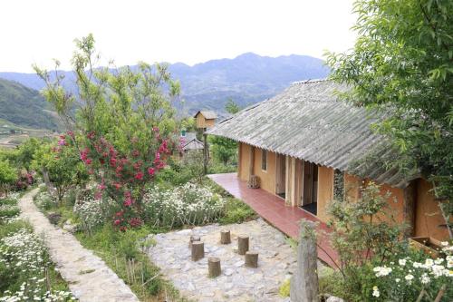 a house with a thatched roof in a garden at H'mông cổ trấn sapa homestay in Sa Pa