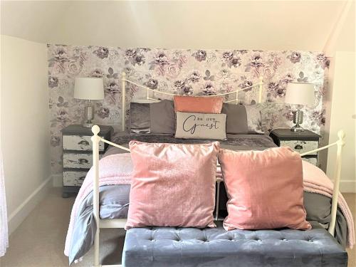 um quarto com uma cama com almofadas cor-de-rosa e rosa em The Dairyman Suite em Dorchester