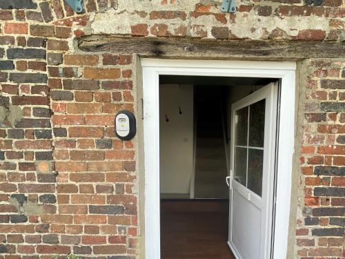a brick building with a white door and a brick wall at The Dairyman Suite in Dorchester