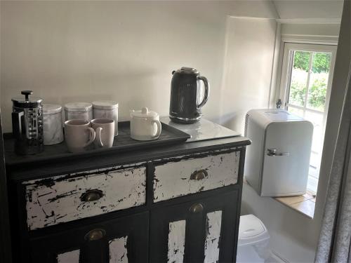 a dresser with cups and mugs on it in a bathroom at The Dairyman Suite in Dorchester
