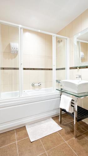 a bathroom with a tub and a sink at KORALLIA GUESTHOUSE Castle Harbour in Los Cristianos