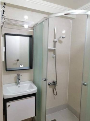 a bathroom with a sink and a shower with a mirror at 3 Pax Studio Foggy Cold Breeze,Condo in Gardenville Hotel in Baguio