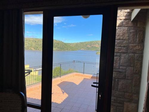 a door to a balcony with a view of a lake at Fish Eagle Bay 28, Warmbaths in Bela-Bela