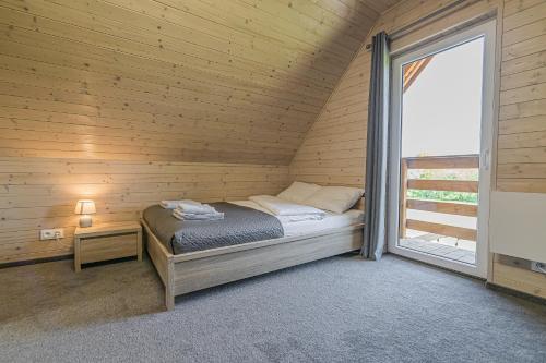 a bed in a wooden room with a window at Wycisznia - drewniane domki całoroczne in Gierałtowiczki