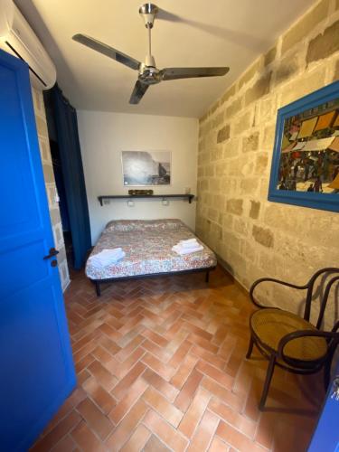 ファヴィニャーナにあるBaglio Del Pifferoのベッド1台と天井ファン付きの客室です。