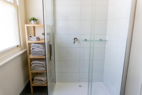 a shower with a glass door in a bathroom at Pound Hill Cottage in Miners Rest