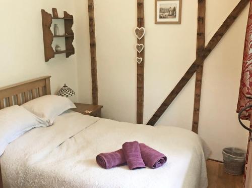 a white bed with two purple towels on it at Drovers Retreat in Llandrindod Wells