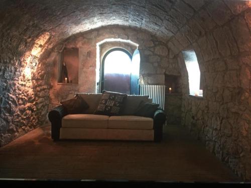 a couch sitting in a room with a stone wall at La pietra in Roccamorice