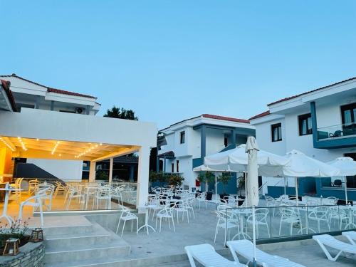 a patio with white chairs and tables and buildings at Acrotel Lily Ann Village in Nikiti