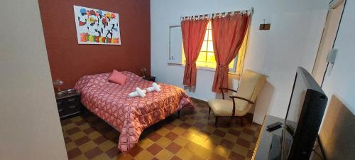 a bedroom with a bed and a chair and a window at Casa de La Lila in Salta