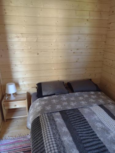 a bedroom with a bed in a wooden room at słoneczny domek II in Kołczewo