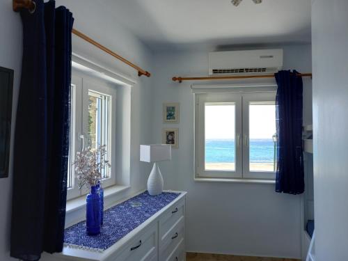 um vaso azul num balcão num quarto com uma janela em Anthie's shore house em Istérnia