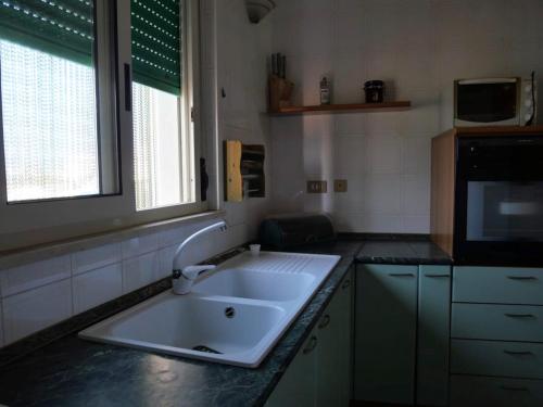 uma cozinha com um lavatório branco e um micro-ondas em 100 passi dal mare em Isola delle Femmine