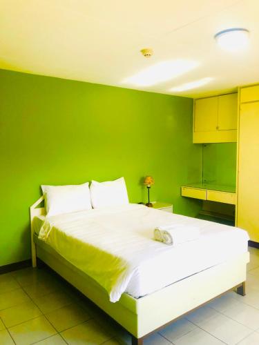 a green bedroom with a white bed with a green wall at Benson Hotel San Juan CIty in Manila