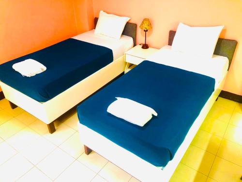 two beds in a room with blue and white at Benson Hotel San Juan CIty in Manila
