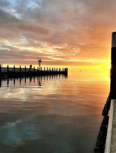 a sunset over a body of water with a pier at Havenhotel At Sea Texel in Oudeschild