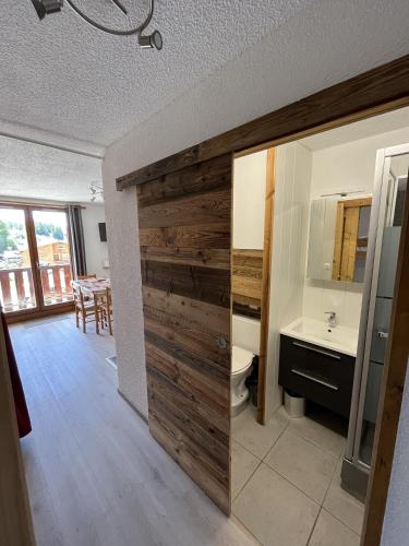 La salle de bains est pourvue d'une porte coulissante en bois, d'un lavabo et de toilettes. dans l'établissement Grand Studio, aux Carroz d'Arâches