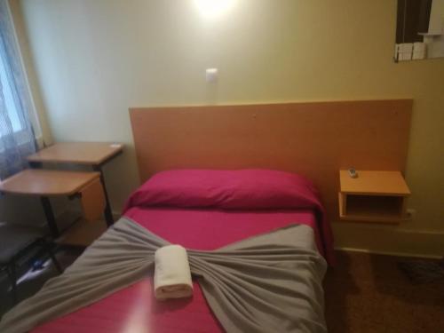 a small bedroom with a bed with a pink blanket at Alojamento Local Pensão Rossio in Lisbon