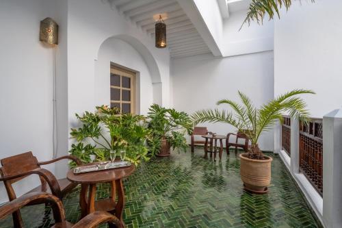a room with potted plants and tables and chairs at Riad Alma in Marrakech