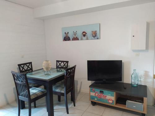 uma sala de jantar com uma mesa e uma televisão em Joli appartement avec grande et belle terrasse, au pied de la plage du Grazel! em Gruissan