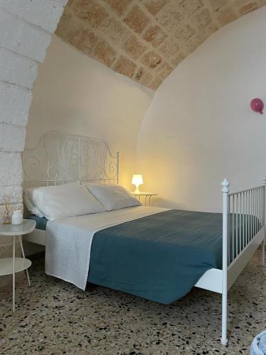 a bedroom with a bed and a table with a lamp at Maison Anthea in Ostuni