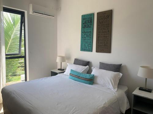 sypialnia z białym łóżkiem z 2 lampami i oknem w obiekcie Azuri Apartment 8 w mieście Roches Noires