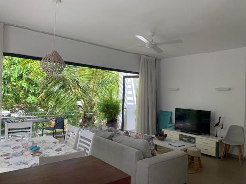 a living room with a couch and a table and a tv at Azuri Apartment 8 in Roches Noires