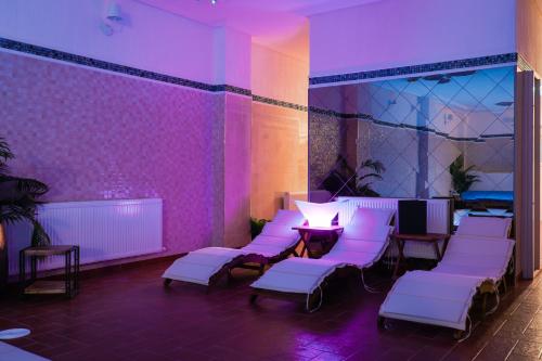 um quarto com cadeiras brancas e iluminação roxa em Hotel Bloom em Caciulata
