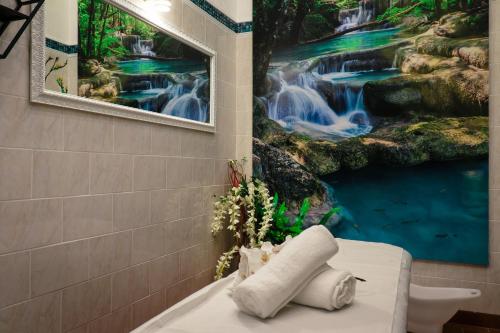 a bathroom with a waterfall painting on the wall at Hotel Bloom in Caciulata