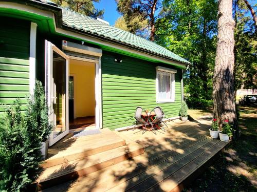 a green cabin with a wooden deck in front of it at G3 in Palanga