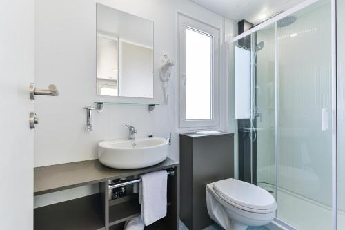 een badkamer met een wastafel, een toilet en een douche bij Adria Nova kamp Laguna in Turanj