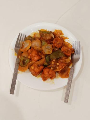 a plate of food with chicken and vegetables with two forks at Mayda Inn- A Boutique Hotel in New Delhi