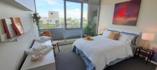 a bedroom with a bed and a large window at beautiful apartment 100mts near the beach in Port Melbourne in Melbourne