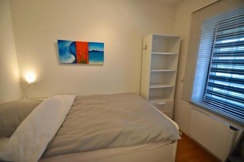 1 dormitorio con 1 cama y una pintura en la pared en Strandperle, en Friedrichskoog