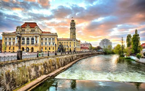 a river in front of a building with a clock tower at Private Apartment in the City Centre. in Oradea
