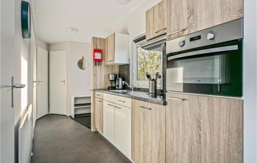 a kitchen with wooden cabinets and a stove top oven at 3 Bedroom Stunning Home In Lauwersoog in Lauwersoog