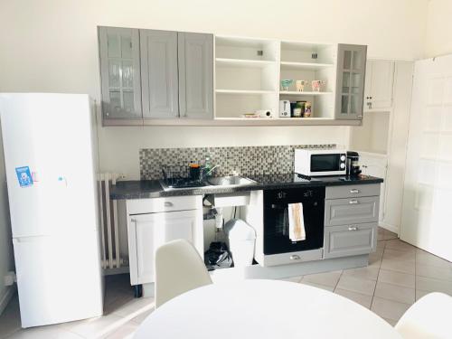 une cuisine avec des armoires blanches, un évier et un micro-ondes dans l'établissement Charmant 4 pièces à 100 m de la plage, à Nice