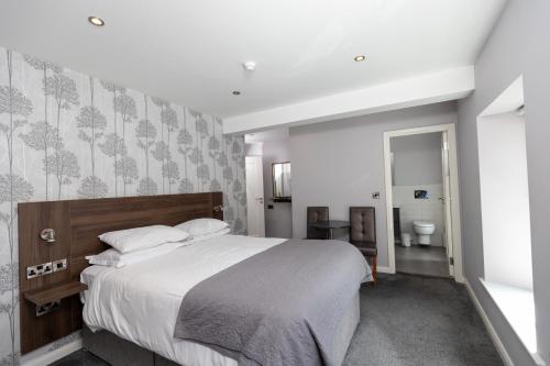 a bedroom with a large bed and a bathroom at Bugler Doyles Bar & Townhouse in Wexford