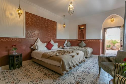 a hotel room with two beds and a chair at Riad Dar Yema in Marrakesh