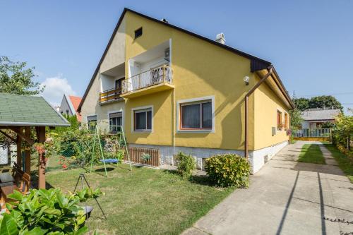 a yellow house with a balcony and a yard at Katica Apartment in Balatonszárszó