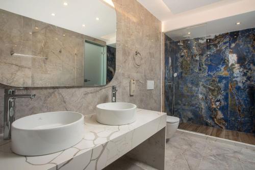 a bathroom with two sinks and a mirror at Lindos White Hotel & Suites in Líndos