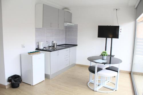 a kitchen with white cabinets and a table and a stool at Casa Dona Ana in Carviçais