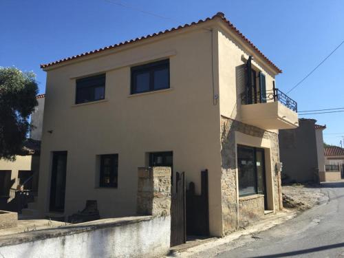 a white house with a balcony on a street at Lemnian house in Portiano in Pedhinón