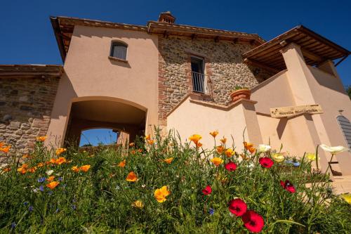 a building with a field of flowers in front of it at Sorelle Biologiche in Monte Castello di Vibio