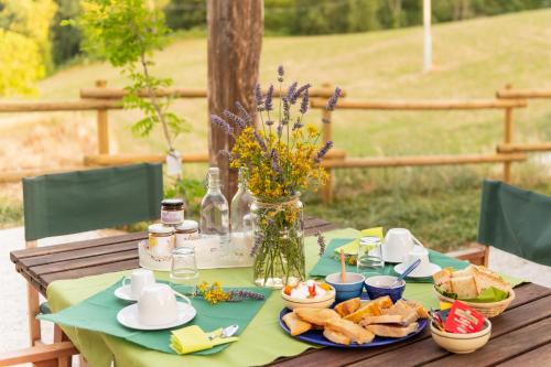 a table with plates of bread and a vase of flowers at Sorelle Biologiche in Monte Castello di Vibio