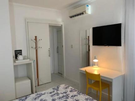 a bedroom with a bed and a table and a desk at Village pé na areia com limpeza in Lauro de Freitas
