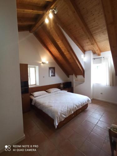 een slaapkamer met een groot bed in een kamer met houten plafonds bij Apartmani Passer in Prvić Luka