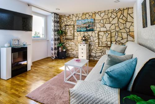 sala de estar con sofá y pared de piedra en JMJ apartmaji Piran, en Piran