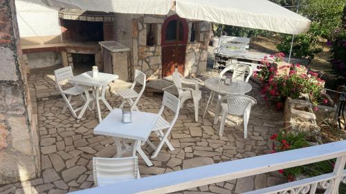 a patio with white tables and chairs and an umbrella at House Villa Anna in Polignano a Mare